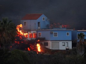 Lava from the Cumbre Vieja volcano burns a house on the Canary Island of La Palma, as seen from Tajuya, Spain, October 19, 2021.