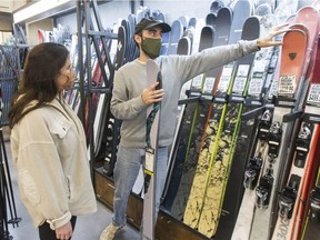 In anticipation of the upcoming ski season, Holly Mitchell shops for new skis with the help of salesman Jack Czarnecki at Comor Sports in Vancouver on Oct. 14. Ski hills throughout B.C. are facing seasonal staff shortages, in part, due to COVID-19.
