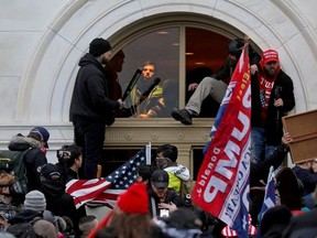 A mob of supporters of then-U.S. President Donald Trump climb through a window they broke as they storm the U.S. Capitol Building in Washington, U.S., January 6, 2021.