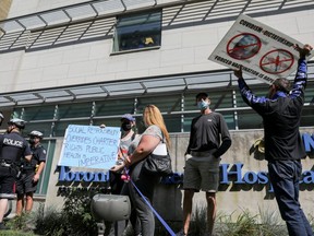Protesters hold signs during an anti-vaccine mandate protest outside Toronto General Hospital in Toronto, Sept. 13, 2021.
