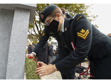 Master Cpl. Christina Reeve of 8 Air Communications and Control Squadron at CFB Trenton places a poppy on a wreath after a Remembrance Day service Thursday, Nov. 11, 2021 in Belleville, Ont. Behind her is Cpl. Andrew Reeve of Trenton's Deputy Wing Command.