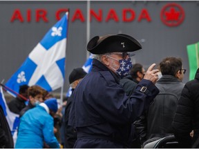 People attend a protest organized by the Société Saint-Jean-Baptiste in front of the Air Canada head office in Montreal on Saturday, Nov. 13, 2021, to denounce the airline's board of directors for keeping CEO Michael Rousseau in his position despite his inability to speak French.