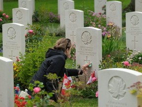 Lise Belanger, 18, cleans the gravestone of her great-uncle, Roger "Sonny" Firman, at the Commonwealth War Graves Commissions Beny-sur-Mer Canadian War Cemetery in Normandy on June 05, 2019 near Reviers, France. Sonny, a 21-year-old serving in the Canadian Royal Winnipeg Rifles, landed on June 6, 1944, at Juno Beach in during D-Day in the Second World War. He was captured by the Germans and on June 8, together with other Canadian prisoners of war, was executed by a unit of the Waffen SS.