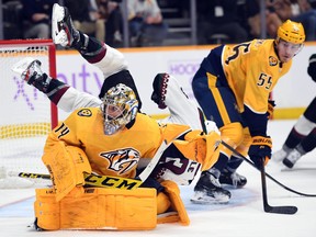 Nashville Predators goaltender Juuse Saros watches the puck in the corner as he is run in to by Arizona Coyotes center Jay Beagle.