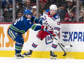 Brock Boeser of the Vancouver Canucks tries to check Alexis Lafreniere of the New York Rangers.