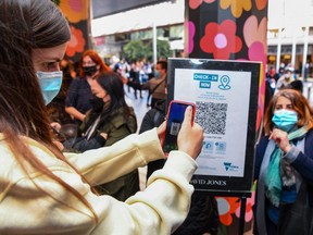 People scan a QR code to enter a department store in Melbourne on Oct. 29, 2021 as the city further lifts COVID restrictions allowing non-essential retail shops to open and travel to the regions of Victoria after the city's sixth lockdown.