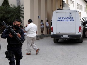 A police officer keeps watch as a vehicle from the coroner's office is parked at the entrance to a hotel after two suspected drug gang members were shot dead in a beachfront clash between rival groups near the Mexican resort of Cancun, in Puerto Morelos, Mexico November 4, 2021.