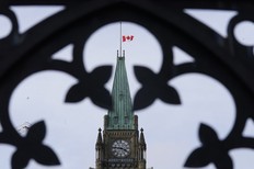 The Canadian flag flies at half-mast over the Peace tower and Parliament buildings Friday, Oct. 22, 2021.