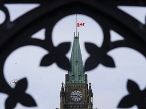 The Canadian flag flies at half-mast over the Peace tower and Parliament buildings Friday, Oct. 22, 2021.