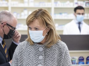 Ontario Health Minister Christine Elliott (centre) trades places at the podium with Dr Kieran Moore (left), Ontario's Chief Medical Officer of Health, at a news conference held in a  Toronto pharmacy  on Thursday, November 18, 2021.