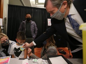 Toronto Mayor John Tory places a sticker on one of the first children in Canada to be vaccinated at the Metro Toronto Convention Centre, in Toronto, Tuesday, Nov. 23, 2021.