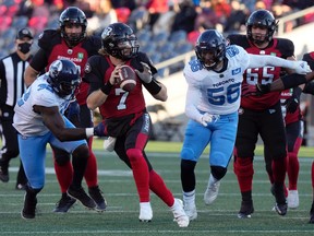 Ottawa Redblacks quarterback Devlin Hodges scrambles under pressure from Toronto Argonauts defensive lineman Cordarro Law (left) and defensive lineman Shane Ray, right, during CFL action, Saturday, Nov. 6, 2021 in Ottawa.