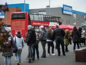 People stand in line in front of a bus to get vaccinated against COVID-19, on November 17, 2021, amid the novel coronavirus / COVID-19 pandemic.