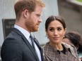 Prince Harry and Meghan Markle looking sombre at war memorial.