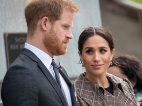 Prince Harry and Meghan Markle looking sombre at war memorial.
