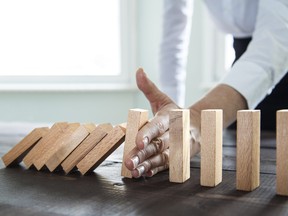 Businesswoman stopping falling wooden dominoes effect