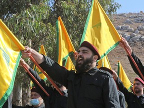 Members of the Lebanese Shiite Hezbollah movement raise party flags as they mark an annual commemoration of a suicide attack against Israeli forces in the Marjayoun region of southern Lebanon, on November 11, 2021.