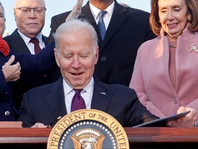 U.S. President Joe Biden celebrates with lawmakers including House Speaker Nancy Pelosi before signing the Infrastructure Investment and Jobs Act on the South Lawn at the White House in Washington, D.C., Nov. 15, 2021.