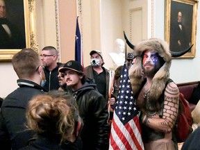 Jacob Chansley, also known as Jake Angeli, of Arizona, stands with other supporters of U.S. President Donald Trump as they demonstrate on the second floor of the U.S. Capitol near the entrance to the Senate after breaching security defences, in Washington, January 6, 2021.