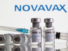 Vials labelled "COVID-19 Coronavirus Vaccine" and sryinge are seen in front of displayed Novavax logo in this illustration taken, February 9, 2021.