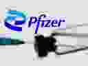 A syringe and vial are seen in front of a displayed Pfizer logo in this illustration PHOTO taken June 24, 2021.