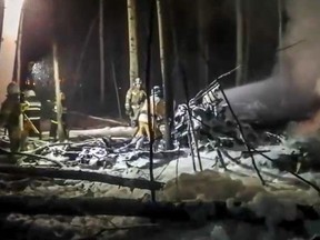 This handout video grab taken and released by the Russian Emergency Situations Ministry on Nov. 3, 2021, shows firefighters working to put out a fire at a site of the Antonov An-12 aircraft crash outside Irkutsk.