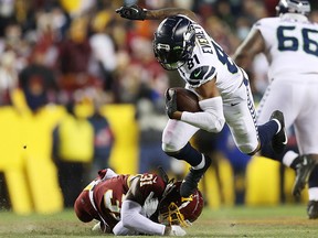 Gerald Everett of the Seattle Seahawks carries the ball after a reception as Kamren Curl of the Washington Football Team defends at FedExField on November 29, 2021 in Landover, Maryland.