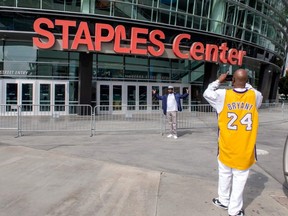 People take photos in front of the Staples Center in Los Angeles, March 14, 2021.