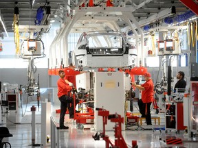 Tesla workers examine a Model S used for training and tool calibration at the company's factory in Fremont, California, June 22, 2012.