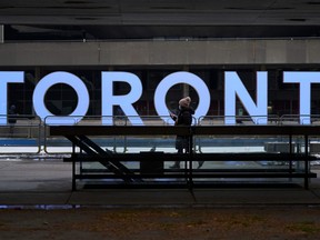 A woman walks past the Toronto sign in Nathan Phillips Square in Toronto on Nov. 23, 2020.