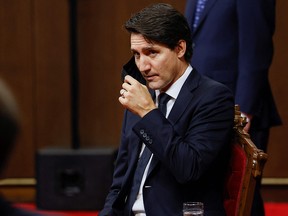 Prime Minister Justin Trudeau removes his mask as he listens to Governor General Mary May Simon (not pictured) deliver the Throne Speech in the Senate chamber in Ottawa November 23, 2021.