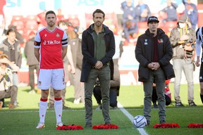 Wrexham owners Ryan Reynolds and Rob McElhenney stand with wreaths as part of remembrance commemorations before the match against Torquay United at Racecourse Ground in Wrexham, Wales, on October 30, 2021. Paul Burrows/Action Images via Reuters