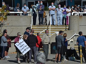 Hospital staff watch as more than 100 people take part in a national day of protest against mandatory vaccination for health-care workers outside the Royal Alexandra Hospital in Edmonton, September 13, 2021.