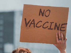 An antivax activist with a sign saying "no vaccine" written on it.
