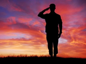 Soldier full body silhouette saluting gesture at sunset copy space