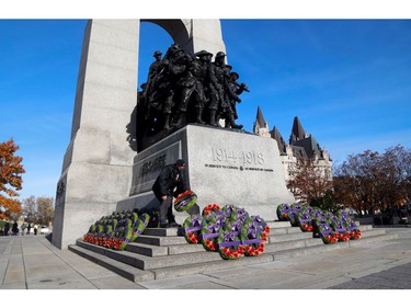 A man lays a wreath of flowers ahead of a ceremony at the National War Memorial on Remembrance Day in Ottawa, Nov. 11, 2021.