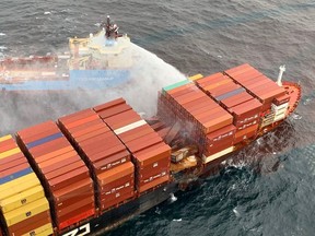 A tugboat pours water on the container ship Zim Kingston after it caught fire off the coast of Victoria, Oct. 25, 2021.