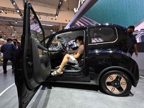 Visitors examine an electric car by Chinese automobile manufacturer Wuling during a car exhibition in Tangerang, Indonesia,  on November 15, 2021.