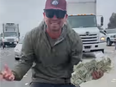 Man with fist full of money after door of armoured truck opens on freeway.