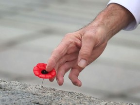 A war vet leaves his poppy on the tomb of the unknown soldier at the National War memorial in Ottawa