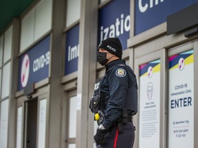 A Toronto Police officer greets people as they arrive the City of Toronto COVID-19 Immunization Clinic at Cloverdale Mall on Saturday, Nov. 27, 2021.