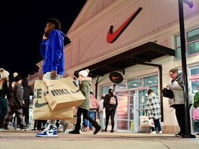 A man with Nike bags talks on the phone in front of a Nike store as Black Friday sales begin at The Outlet Shoppes of the Bluegrass in Simpsonville, Kentucky, U.S., November 26, 2021.