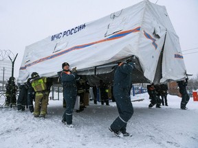 Specialists of Russian Emergencies Ministry carry a tent during a rescue operation following a fire in the Listvyazhnaya coal mine in the Kemerovo region, Russia, November 25, 2021.