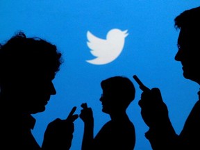 People holding mobile phones are silhouetted against a backdrop projected with the Twitter logo in this illustration picture taken September 27, 2013.