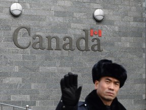 A guard attempts to block photos from being taken outside the Canadian embassy in Beijing on Jan. 27, 2019.