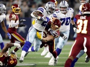 Ezekiel Elliott of the Dallas Cowboys rushes with the ball during the first half against the Washington Football Team at AT&T Stadium on December 26, 2021 in Arlington, Texas.