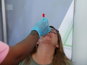A health-care worker collects a swab from a woman for a PCR test against COVID-19 before travelling to London, at O.R. Tambo International Airport in Johannesburg, South Africa, Nov. 26, 2021.