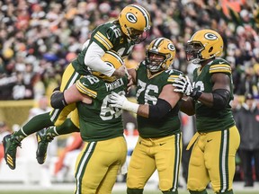 Green Bay Packers quarterback Aaron Rodgers (12) is lifted up by guard Lucas Patrick (62) after setting the franchise record for most passing TDs in the first quarter during the game against the Cleveland Browns at Lambeau Field.