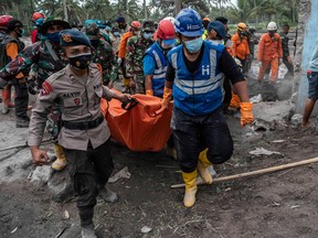 Rescuers carry away a body of a victim at Sumber Wuluh village in Lumajang on December 6, 2021, after the Semeru volcano eruption.