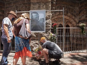 People lay flowers beneath a picture of the late South African Nobel Peace Price Archbishop Desmond Tutu on the wake of his death outside St. George's Cathedral in Cape Town on December 26, 2021.